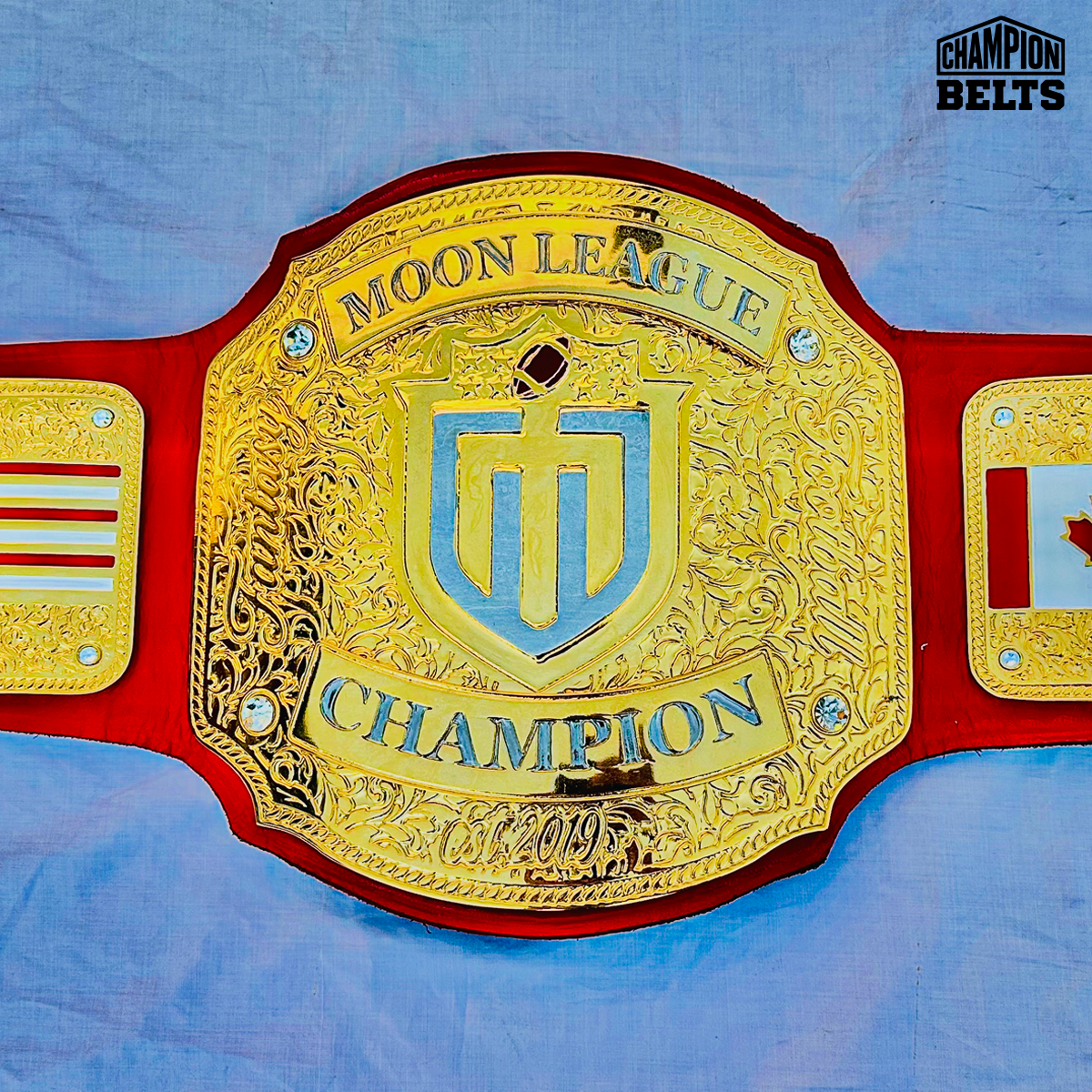 Moon League Championship Belt with gold-tone plates, red strap, sports logo, Champion lettering, crystal accents, and detailed engraving